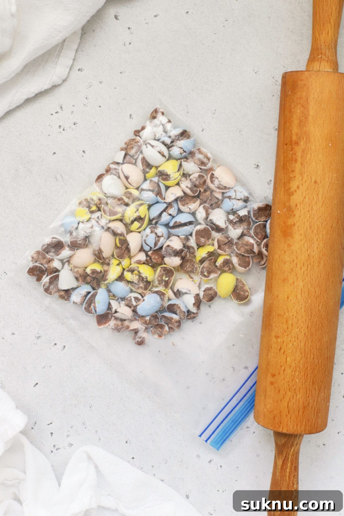 Irresistible Gluten-Free Cadbury Egg Cookies 4 smashing cadbury mini eggs in a ziploc bag with a rolling pin for gluten-free cookies