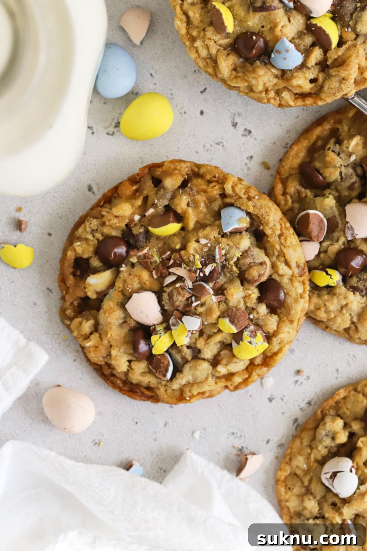 Irresistible Gluten-Free Cadbury Egg Cookies 7 gluten-free cadbury mini egg cookies on a white background with a bottle of milk and more cadbury egg candies scattered around