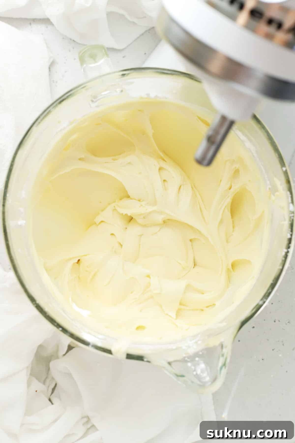 Fluffy cream cheese frosting in the bowl of a stand mixer, ready for decorating gluten-free desserts.