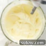 Cream cheese frosting in a stand mixer bowl, ready for piping.