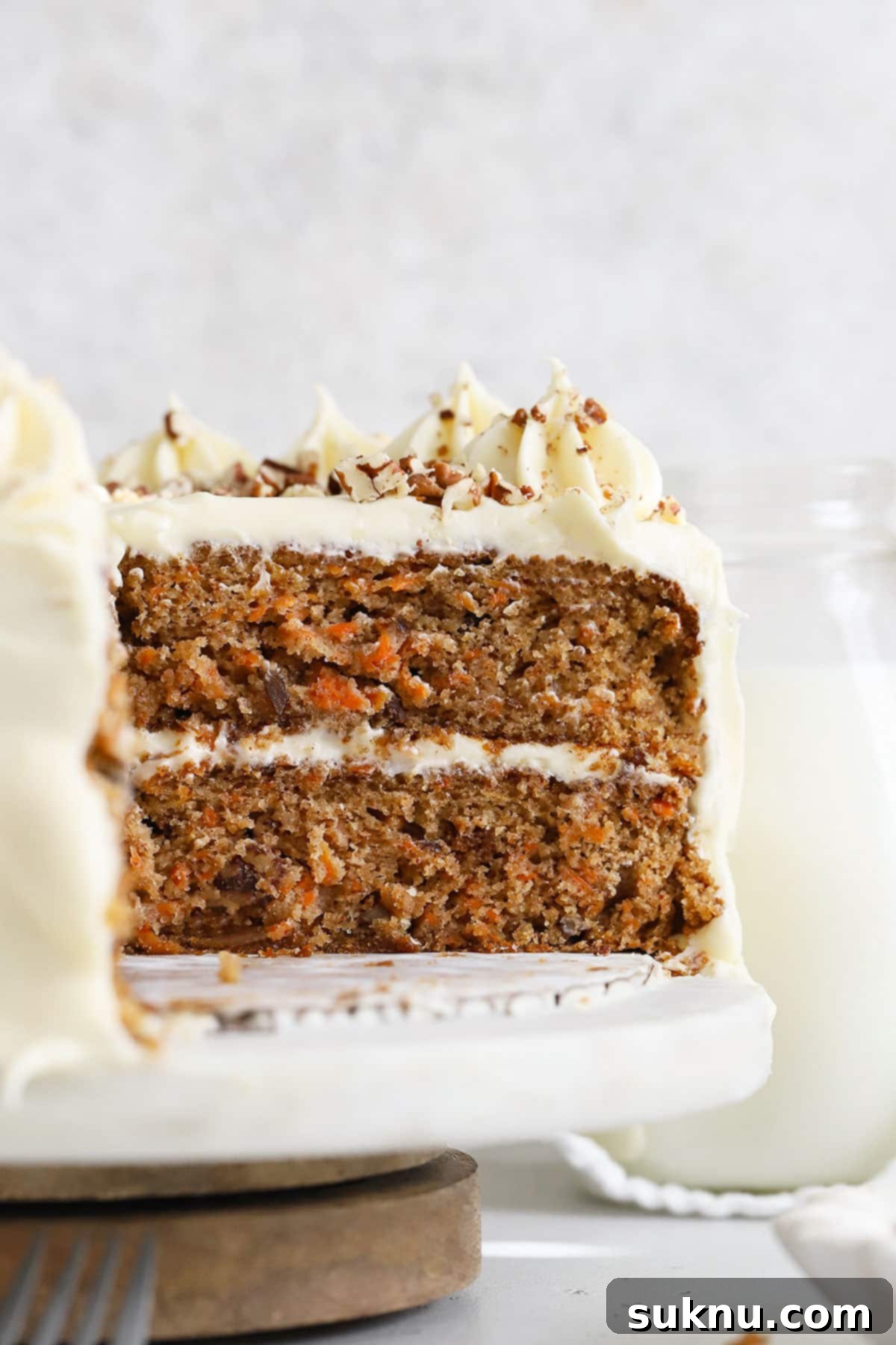 An inside view of a two-layer gluten-free carrot cake generously frosted with smooth cream cheese frosting, showcasing its delicious texture.