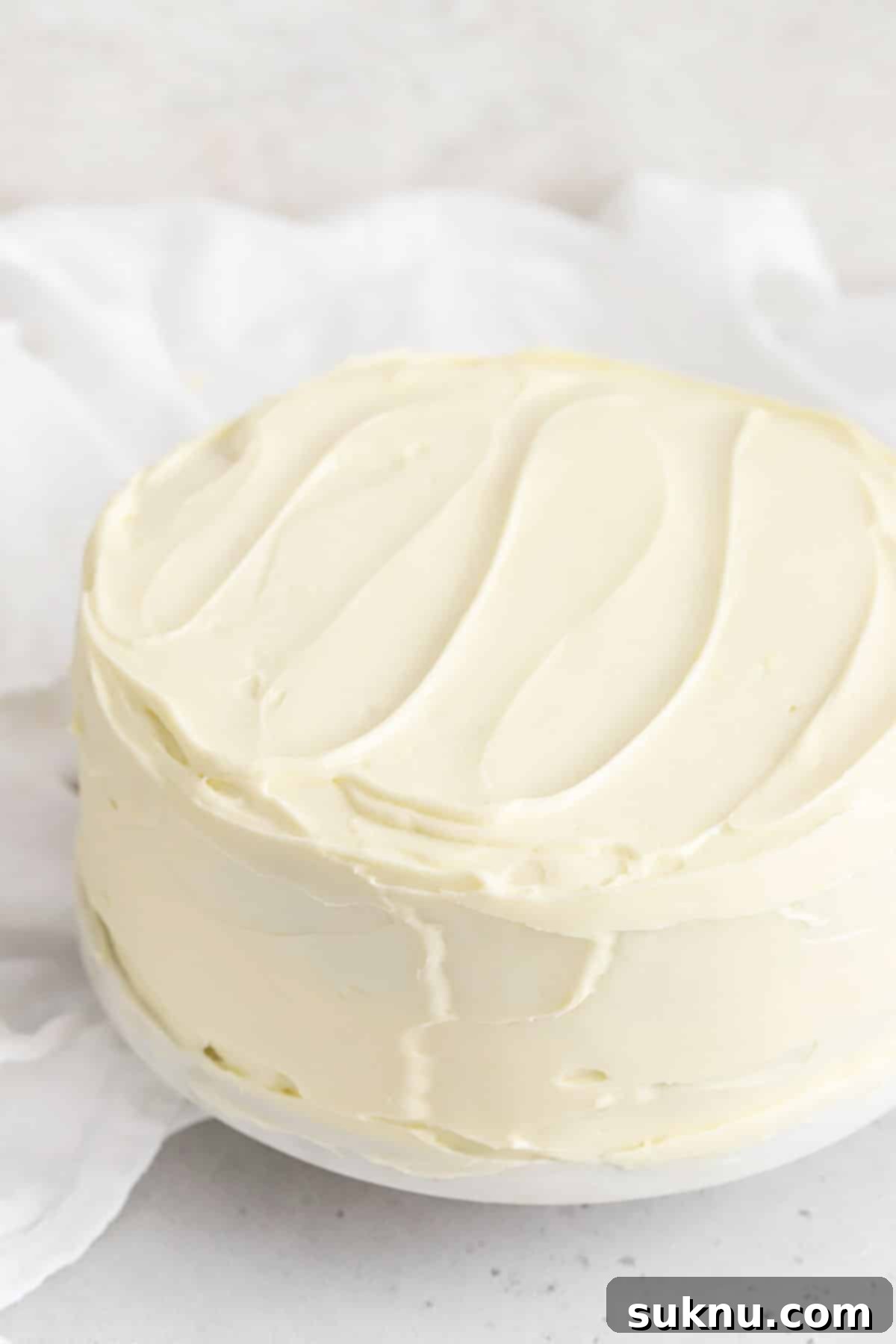 A beautifully decorated two-layer cake frosted with smooth, white cream cheese frosting, ready to be served.