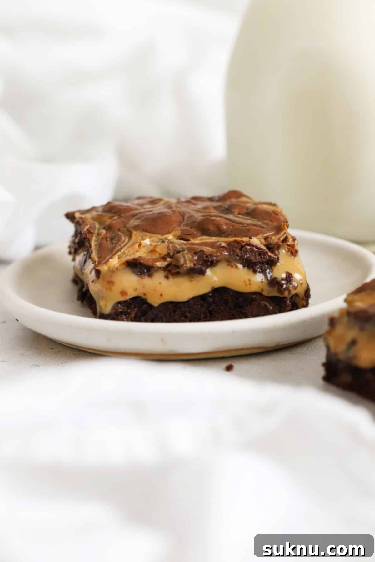 A single square of gluten-free dulce de leche brownie on a white plate, showing its perfect fudginess.