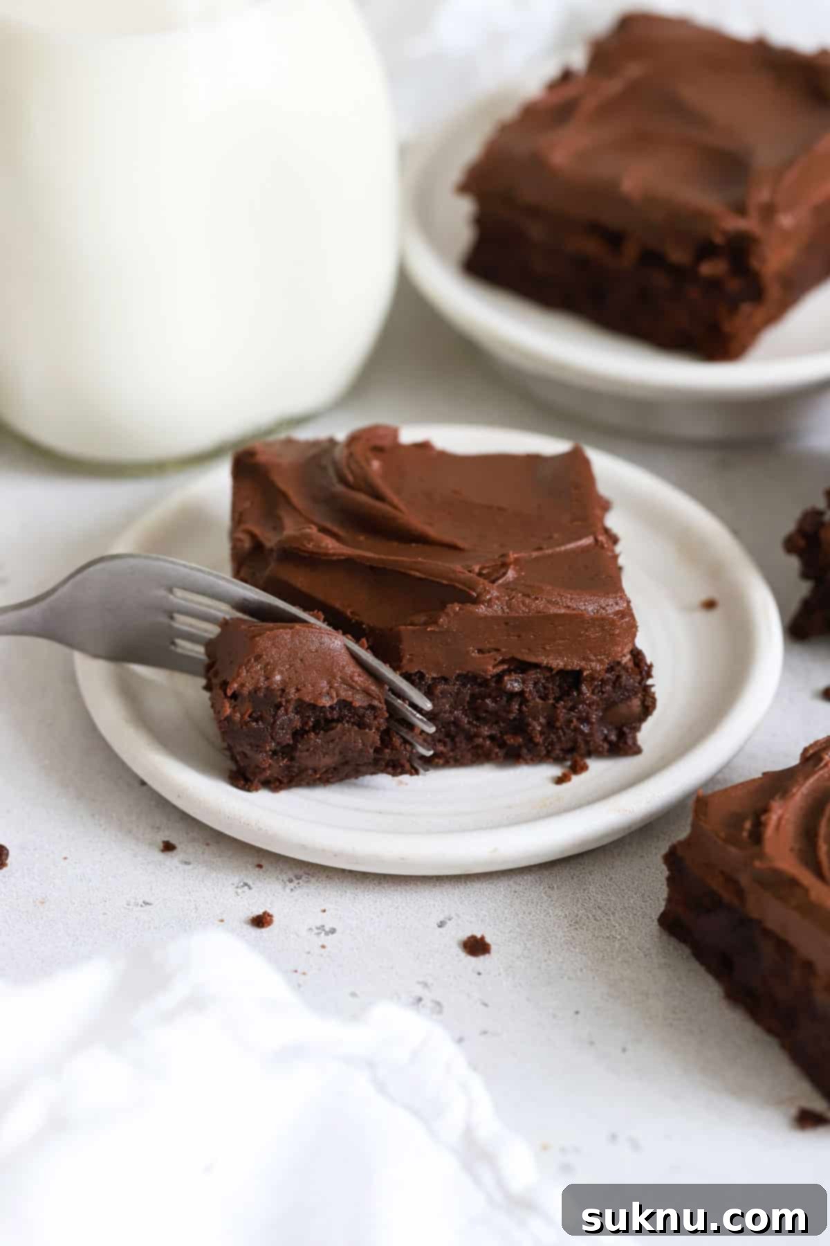 using a fork to take a bite out of a frosted gluten-free brownie