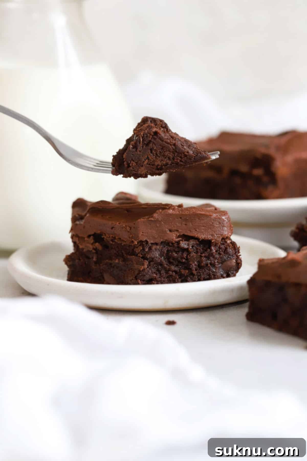 using a fork to take a bite out of a frosted gluten-free brownie