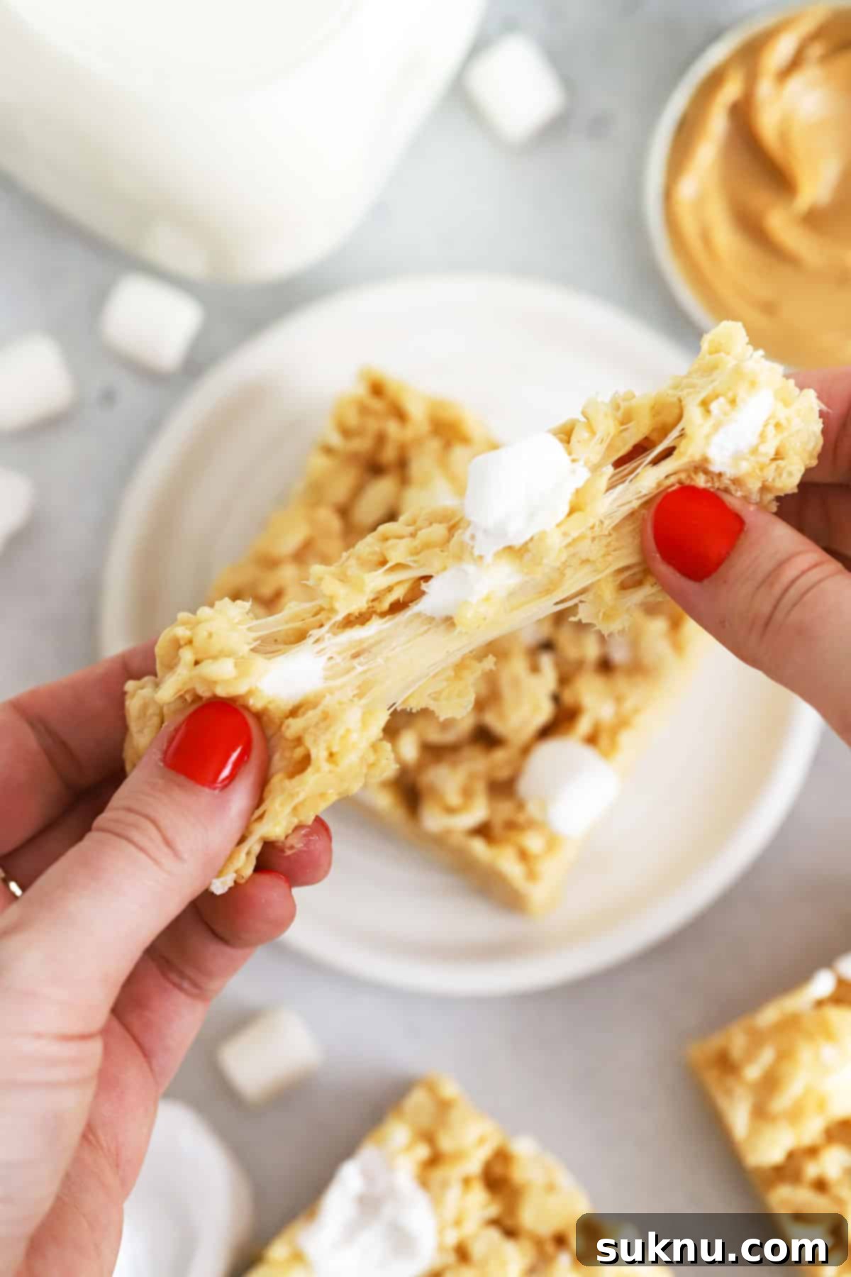 A gluten-free peanut butter rice krispie treat being pulled apart, showing the gooey marshmallow and cereal