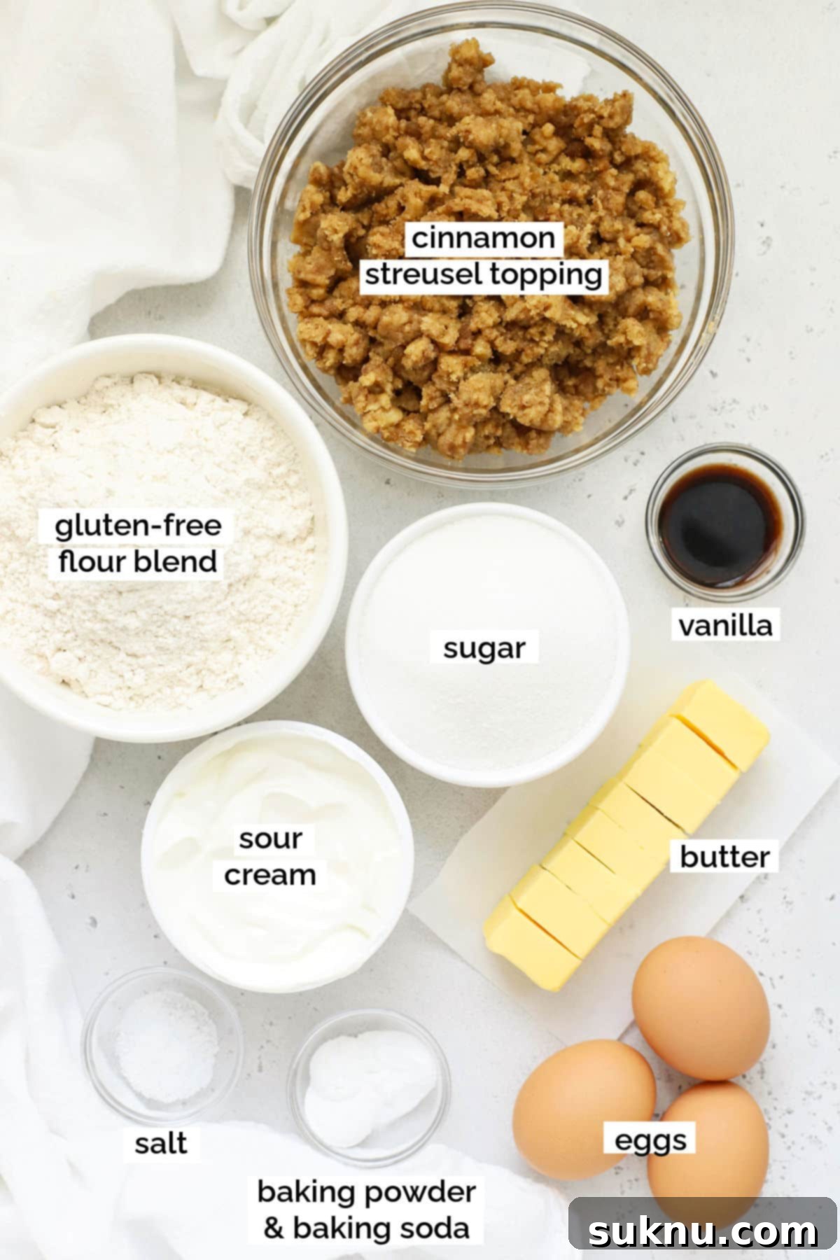 A collection of ingredients for gluten-free cinnamon coffee cake laid out on a surface, ready for baking.