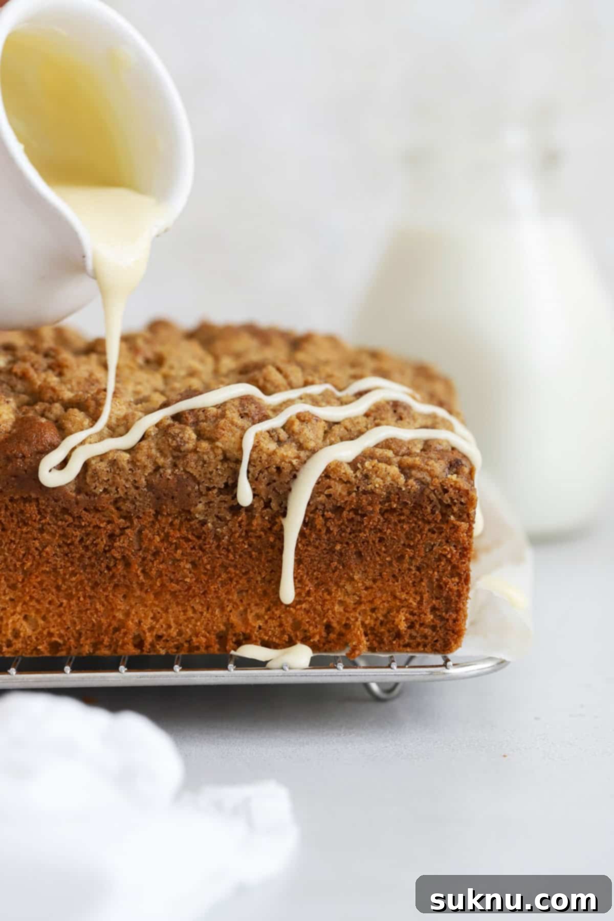 Drizzling a sweet glaze over a freshly baked gluten-free coffee cake, enhancing its appeal.