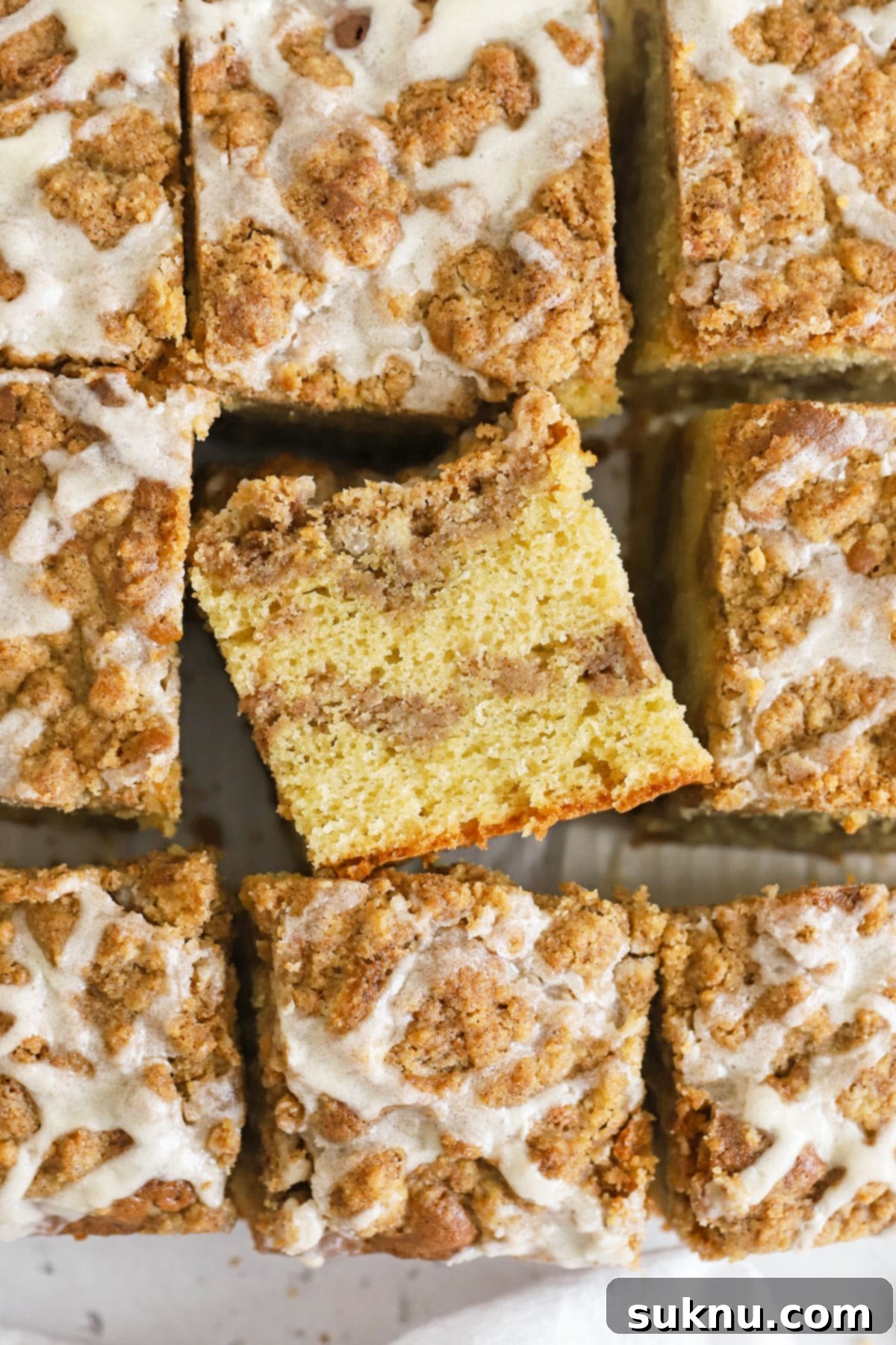 Multiple slices of glazed gluten-free cinnamon coffee cake, beautifully arranged with a scattering of cinnamon.