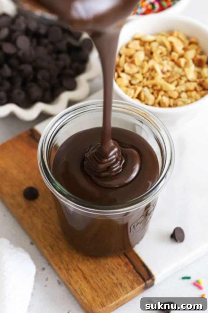 pouring thick homemade hot fudge sauce into a glass jar