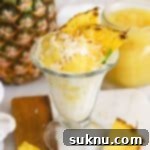 Tropical ice cream sundae with pineapple topping, fresh pineapple, toasted coconut, and macadamia nuts