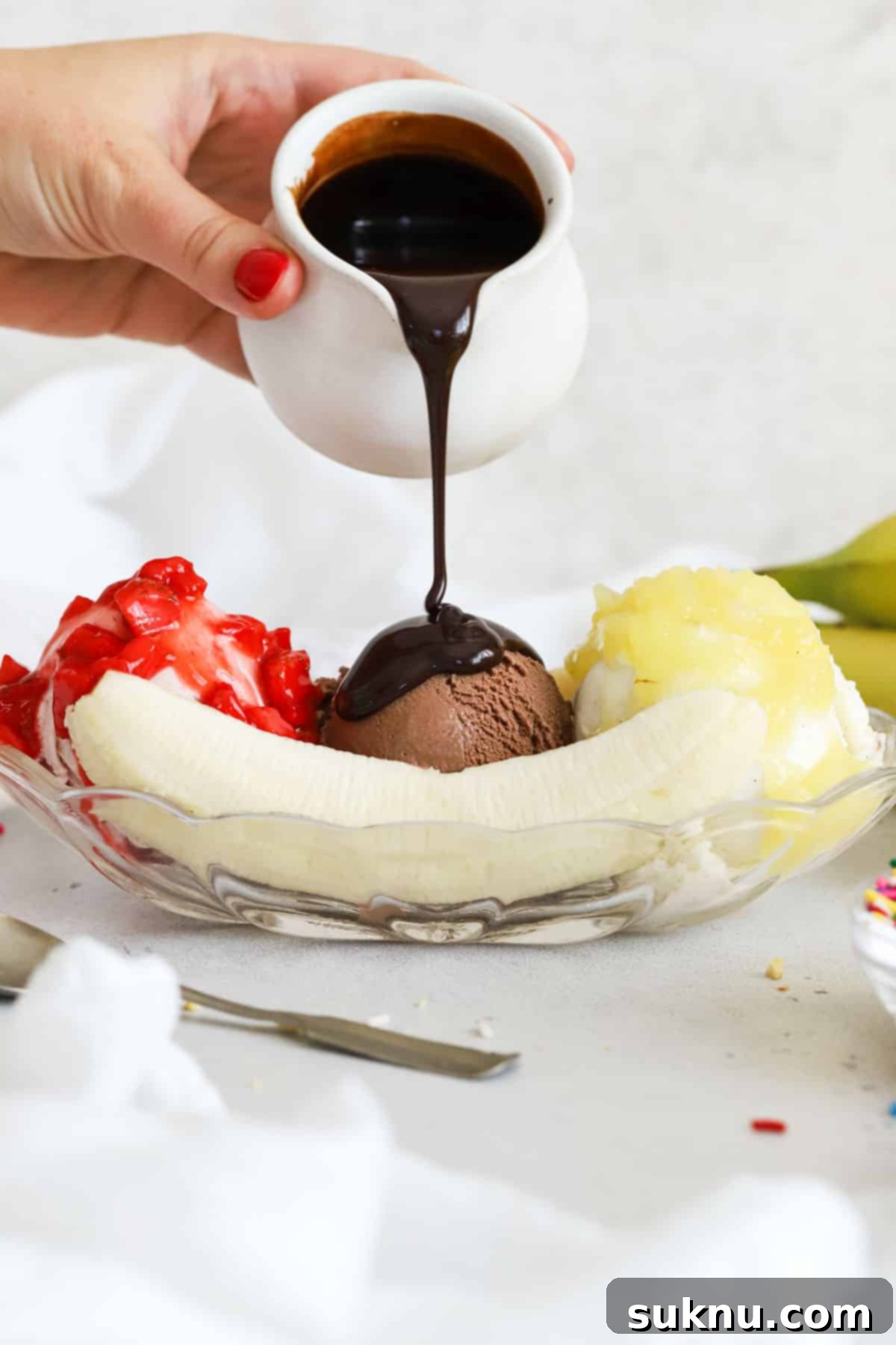 pouring chocolate sauce over a banana split