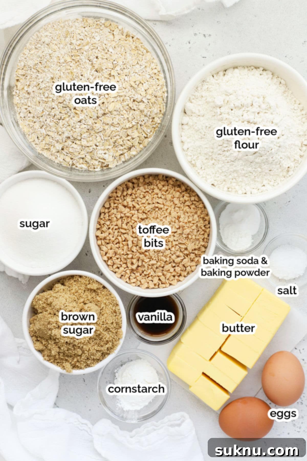 Chewy Gluten-Free Toffee Oatmeal Cookies 3 A collection of fresh, high-quality ingredients laid out for making gluten-free toffee oatmeal cookies, including oats, flour, butter, sugars, eggs, and toffee bits.
