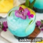 virgin blue hawaiian drink topped with purple flowers and fresh pineapple