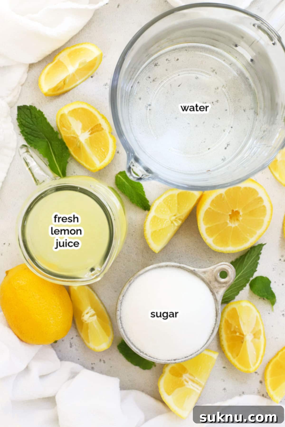 Refreshing Homemade Lemonade 3 A flat lay image displaying the simple ingredients required for old-fashioned lemonade: fresh lemons, granulated sugar, and a pitcher of water.