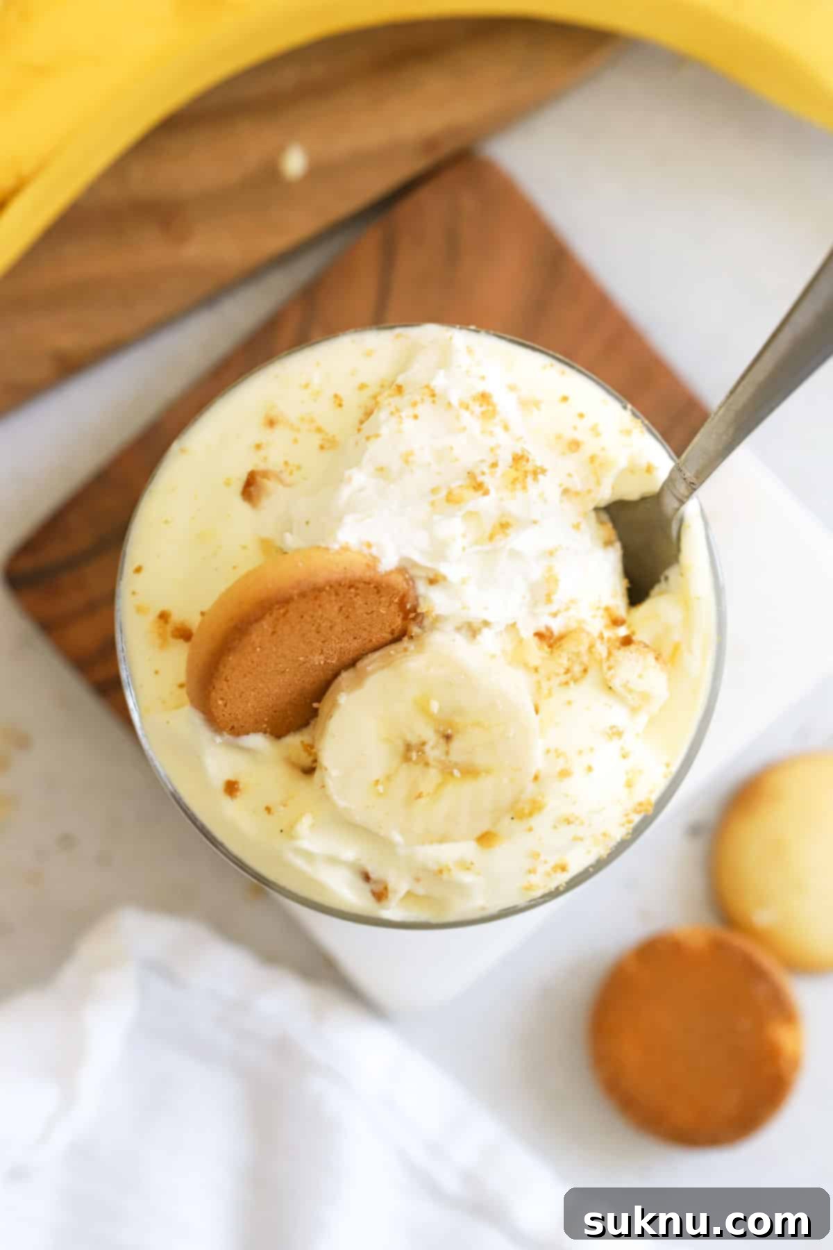 garnishing a bowl of gluten-free banana pudding with whipped cream and banana slices