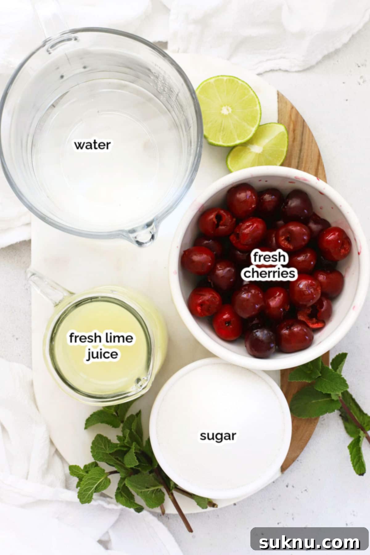 Fresh ingredients for homemade cherry limeade laid out on a table