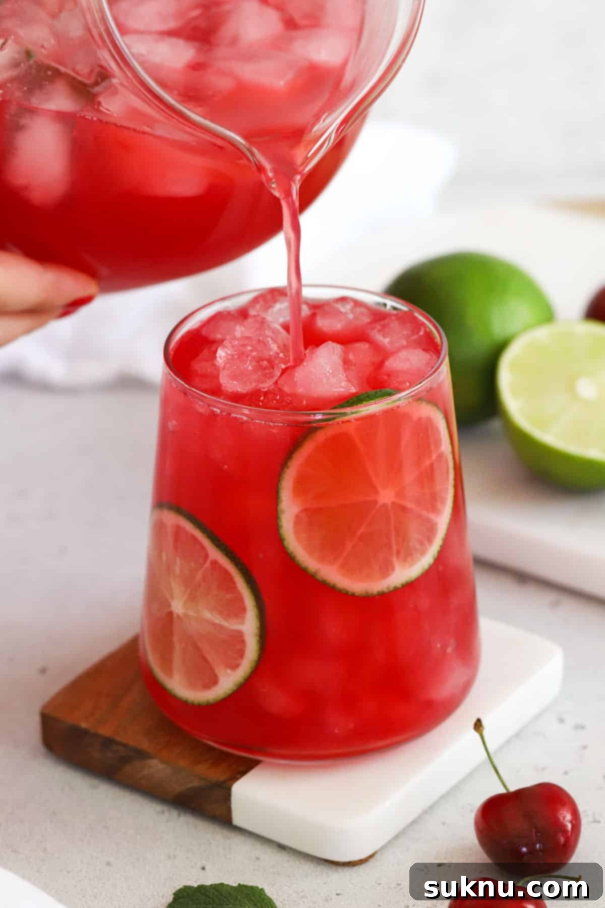 Pouring homemade cherry limeade into a glass over ice