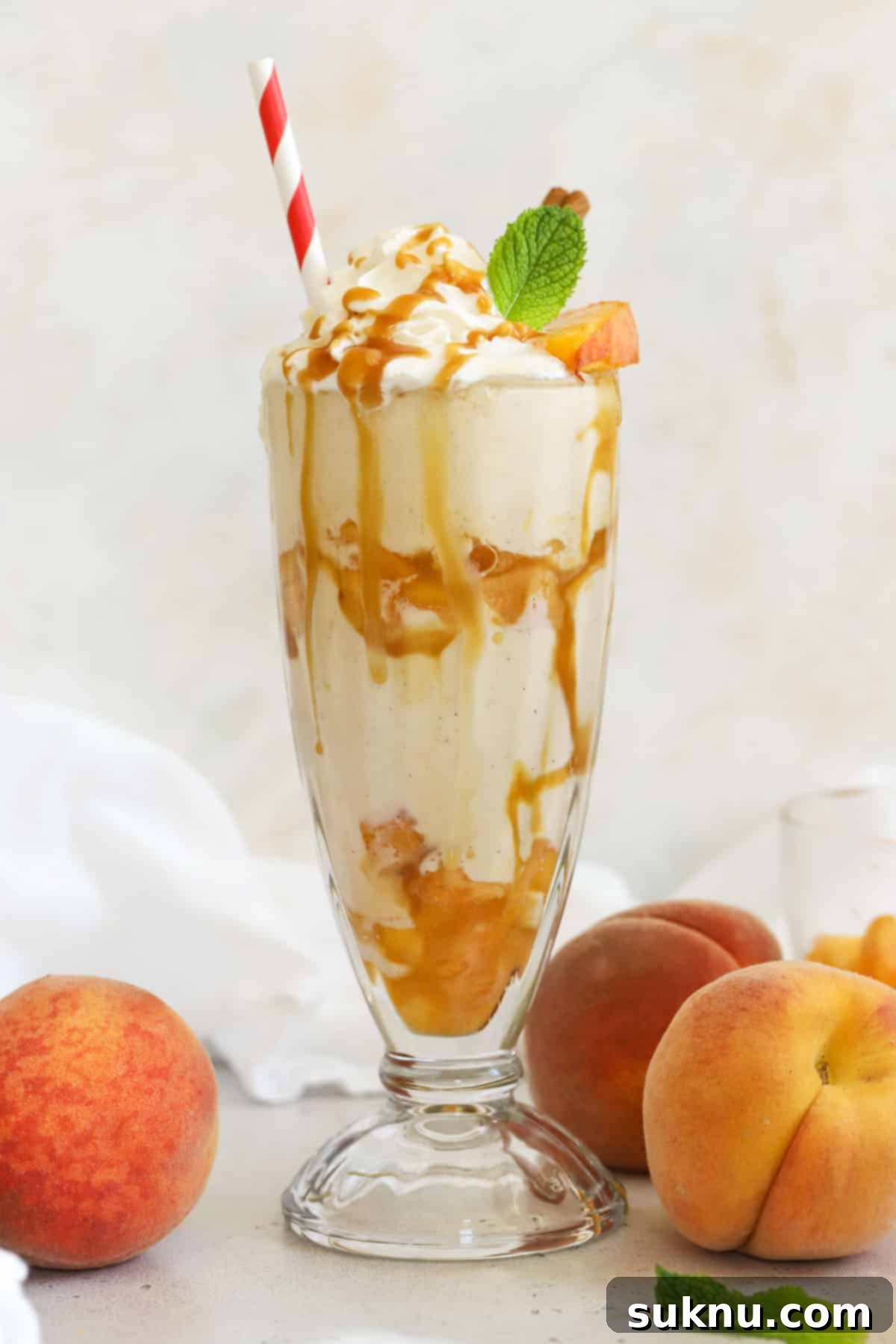 Peachy Dream Shake 5 A beautifully garnished homemade peach milkshake in a tall glass, topped with whipped cream, caramel sauce, and a fresh peach slice.