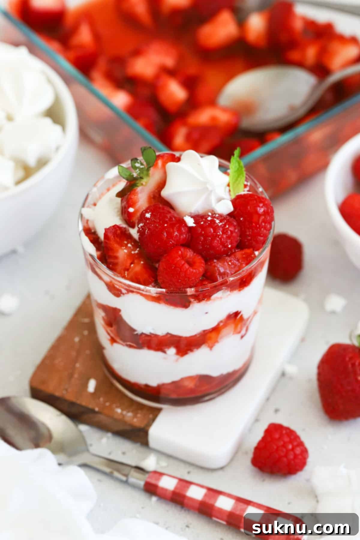Strawberry Eton Mess in a small glass dessert dish, garnished with fresh mint and a whole meringue
