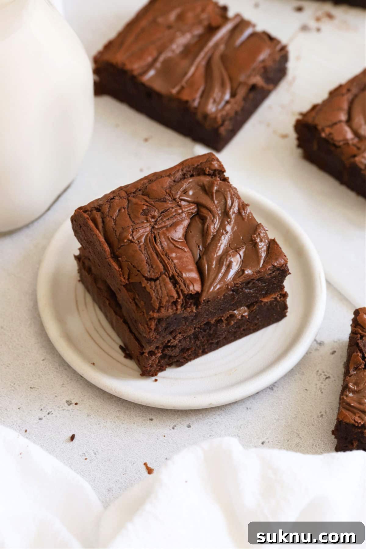 Close-up of a stacked gluten-free Nutella brownie on a white plate, showing the rich texture