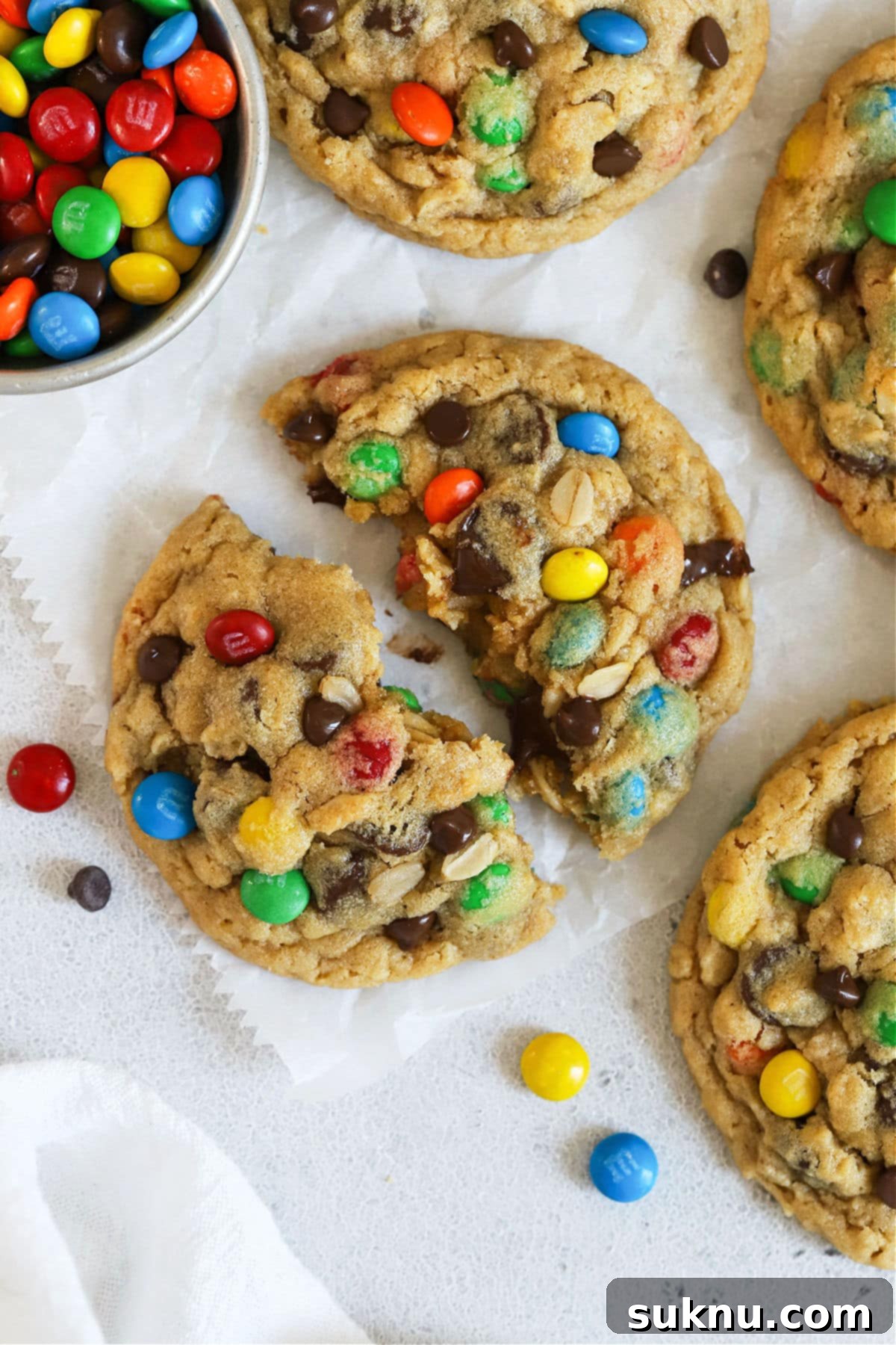 A perfectly baked gluten-free monster cookie broken in half, revealing its soft, chewy interior packed with mix-ins.