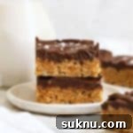 two gluten-free scotcheroos stacked on a white dessert plate