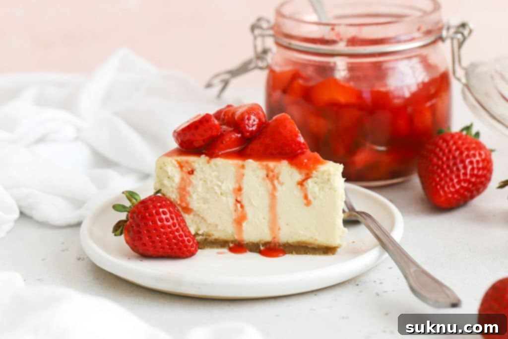 A beautifully presented gluten-free strawberry cheesecake topped with glossy strawberry sauce and fresh berries.