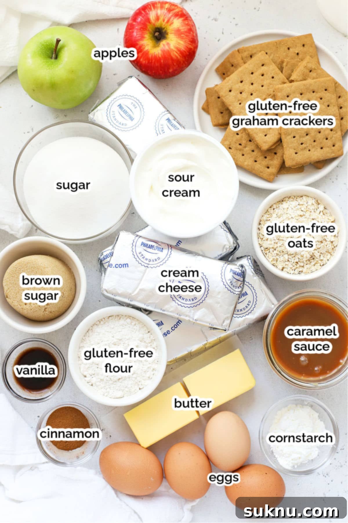Ingredients for making a gluten-free caramel apple cheesecake laid out on a kitchen counter.
