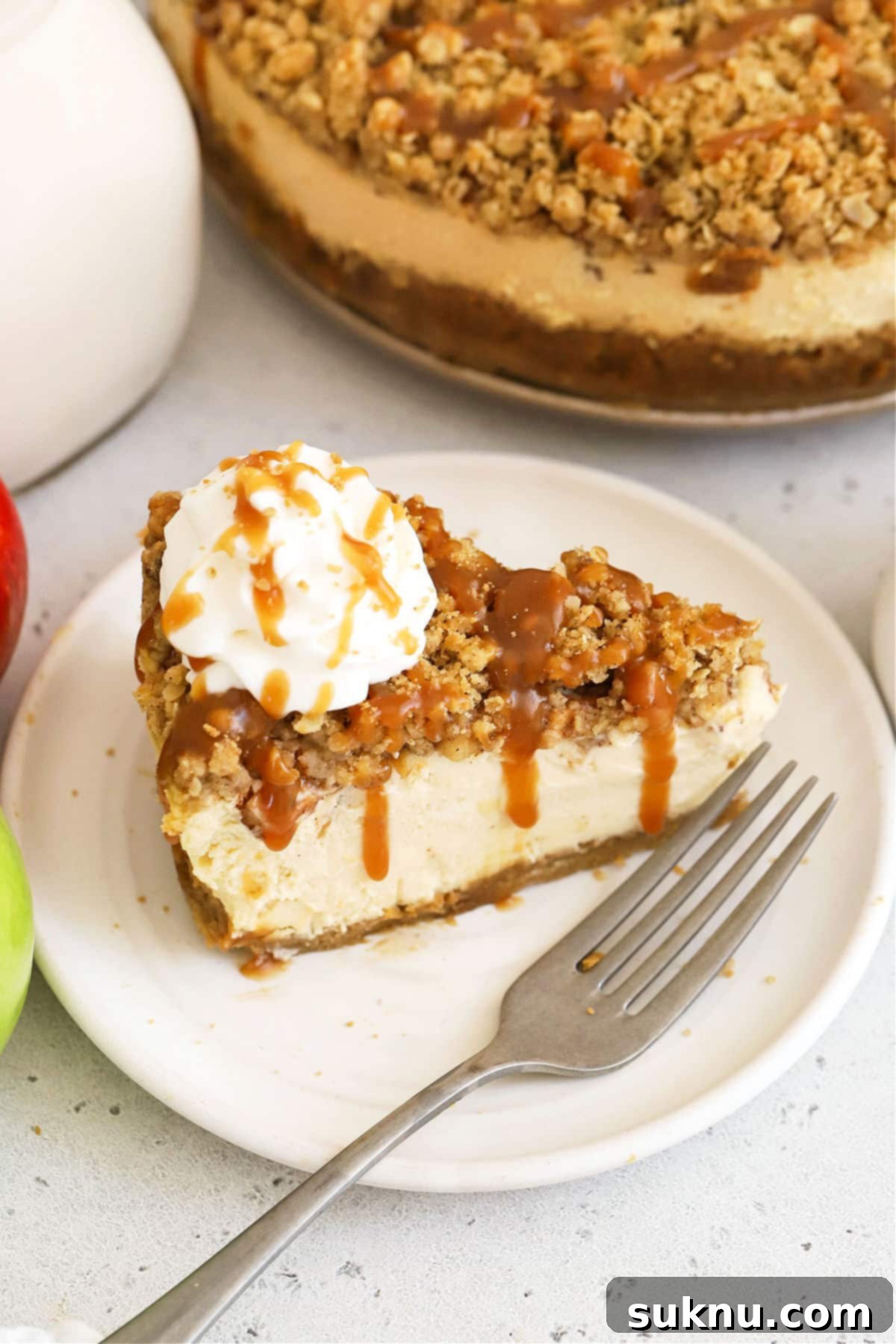 Close-up of a gluten-free caramel apple cheesecake topped with whipped cream, ready to serve.
