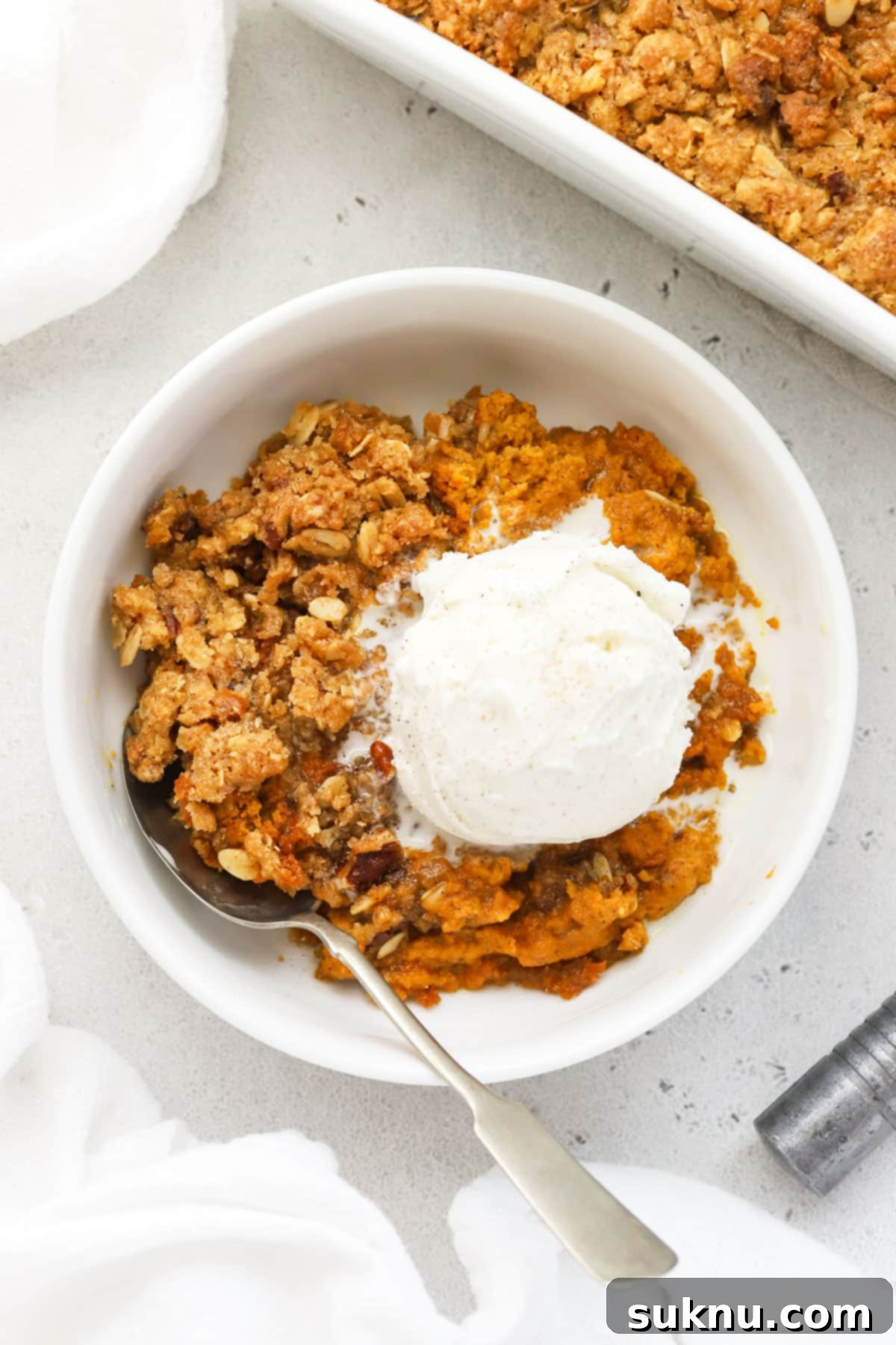 Cozy Gluten-Free Pumpkin Crisp 12 A bowl of gluten-free pumpkin crisp, artfully topped with a scoop of creamy vanilla ice cream, making it an inviting dessert.