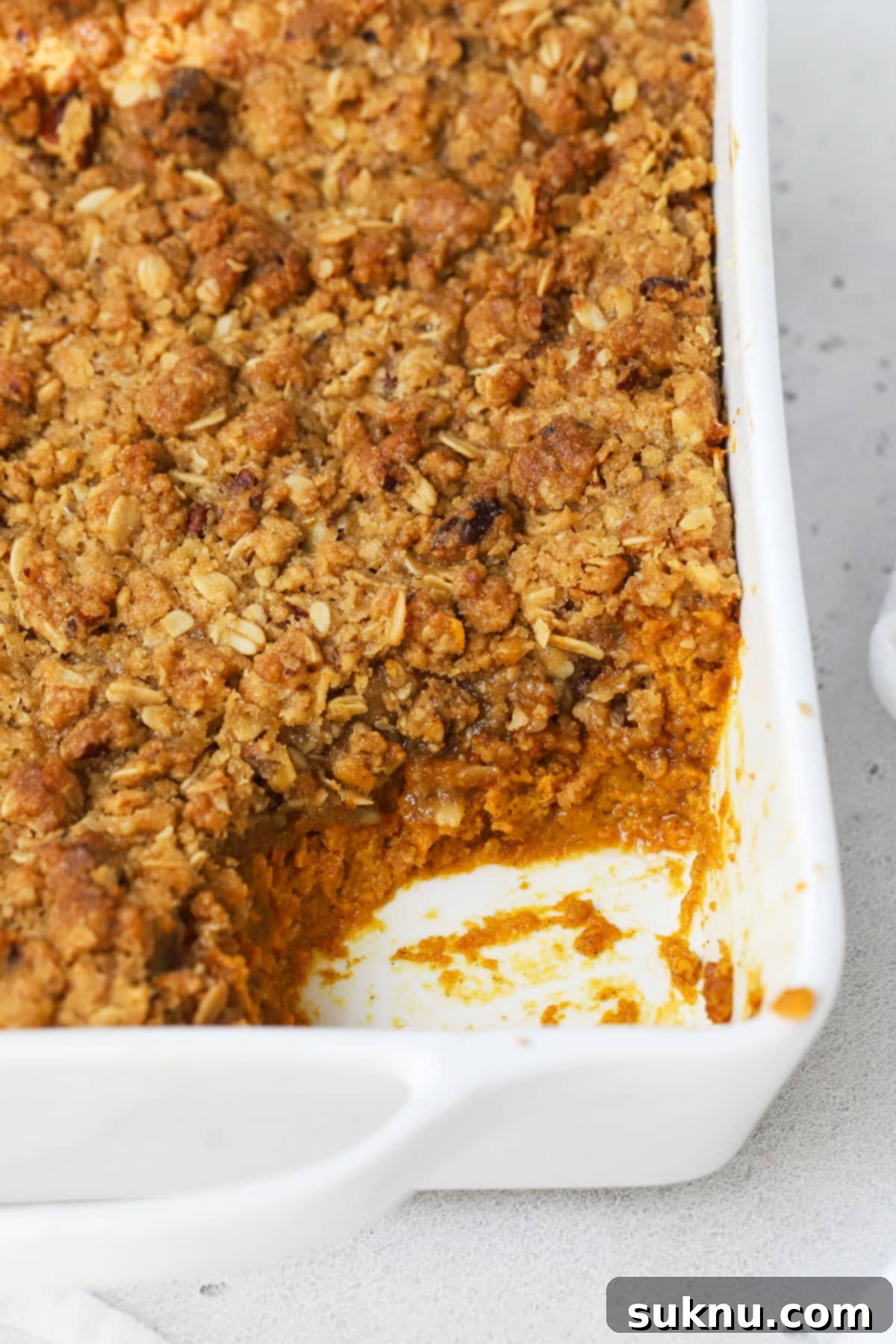 Cozy Gluten-Free Pumpkin Crisp 6 A scoop has been taken out of a gluten-free pumpkin crisp, revealing the creamy filling and crunchy topping.