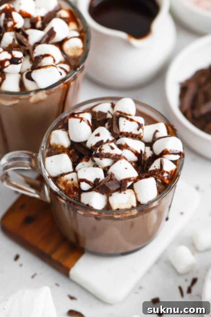 Enchanted Pumpkin Elixir 10 two glass mugs of gluten-free hot chocolate with marshmallows, chocolate syrup, and chocolate shavings