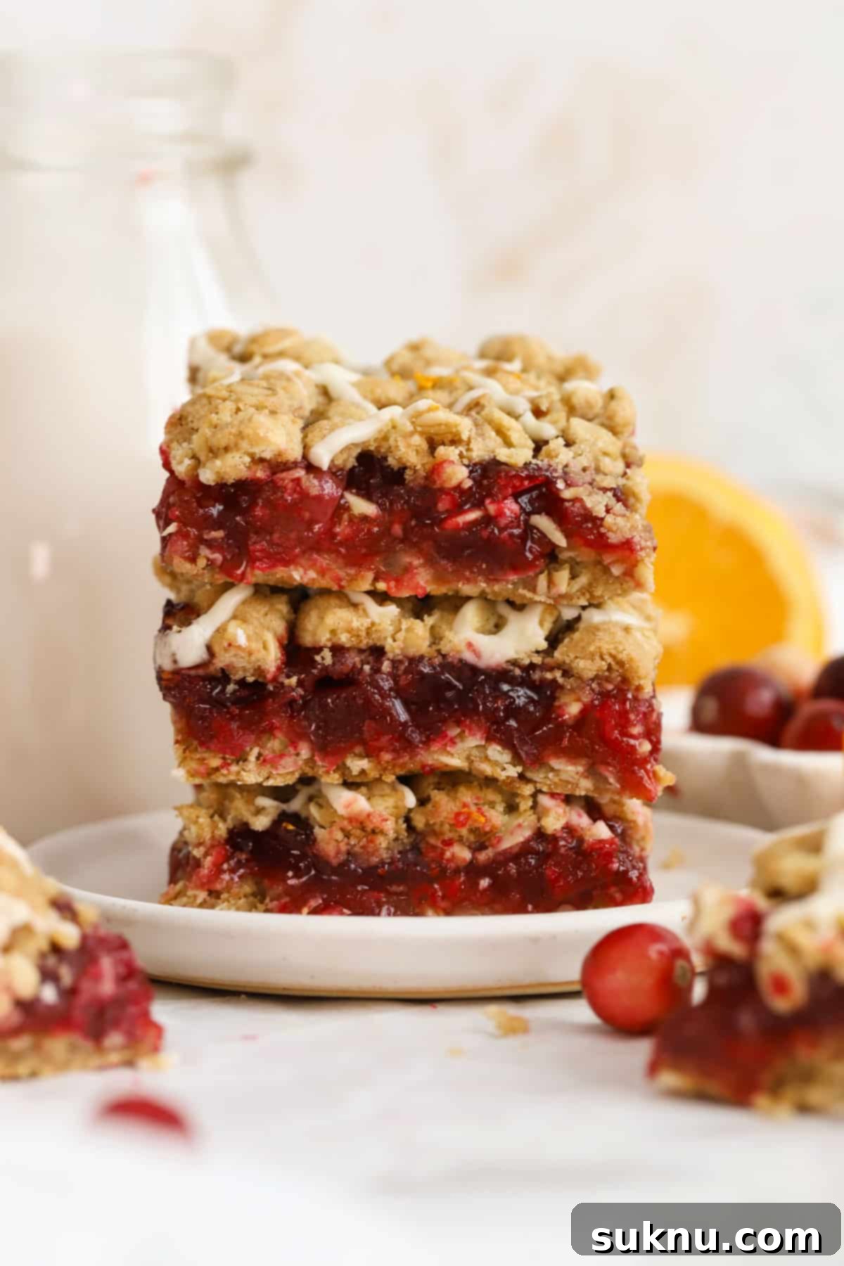 Stacked gluten-free cranberry crumble bars on a white plate, showcasing the crumbly top and rich cranberry filling.