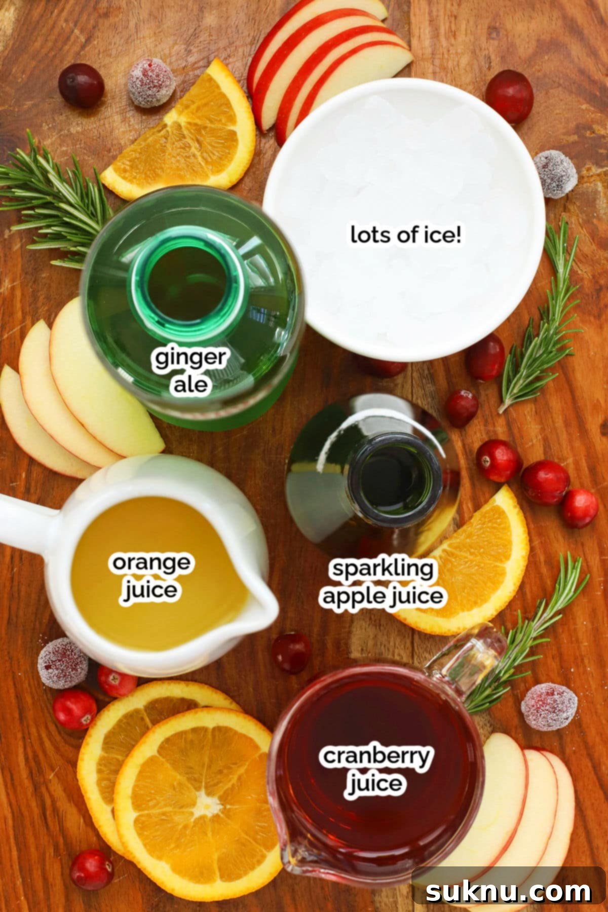 Holiday punch ingredients on a wooden cutting board, including cranberry juice, orange juice, sparkling cider, and ginger ale