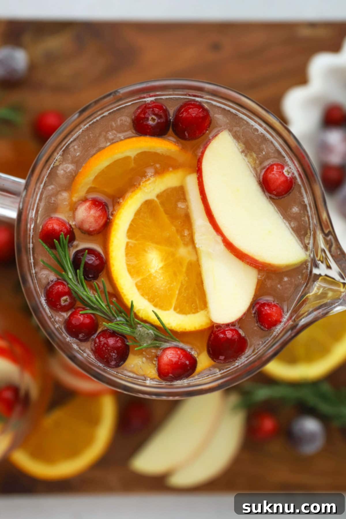 Christmas punch in a hobnail pitcher, surrounded by fresh cranberries and pinecones