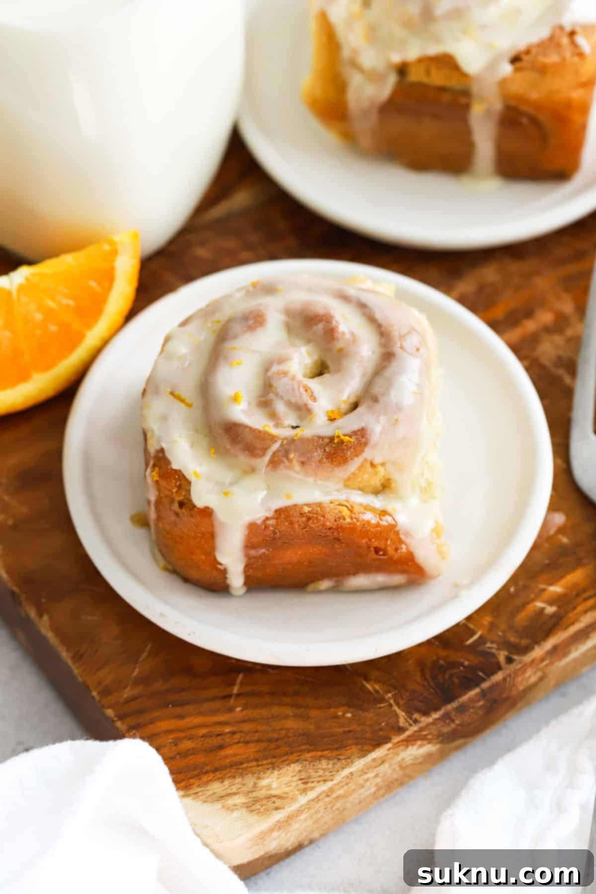 A plate of golden-brown gluten-free orange rolls with a luscious orange glaze.
