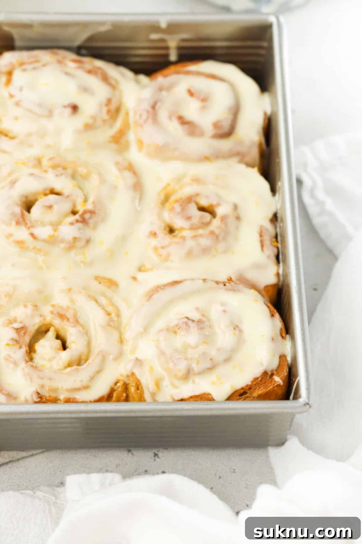 A baking pan filled with homemade gluten-free orange sweet rolls, golden brown and ready for frosting.