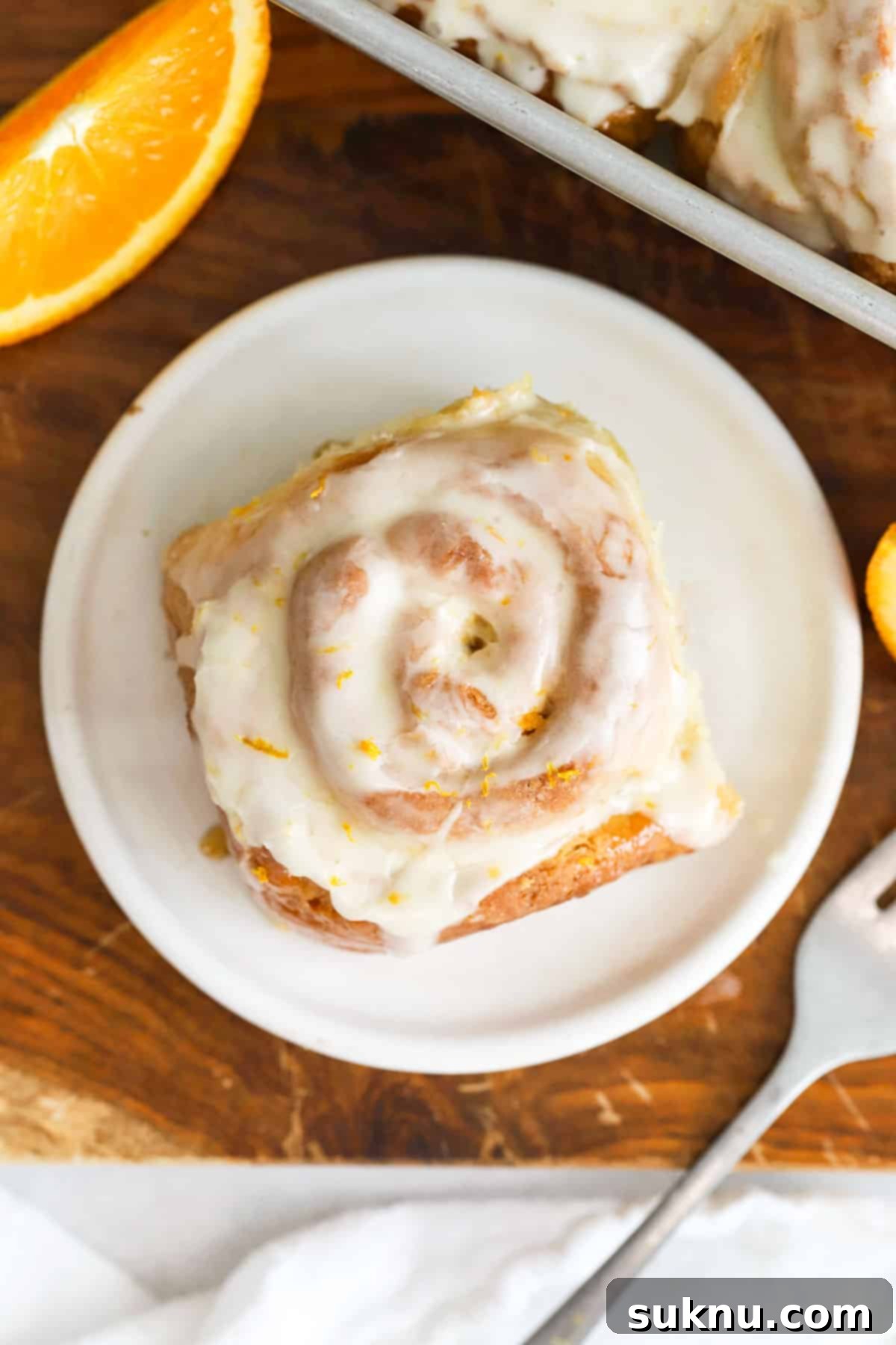 Gluten-free orange rolls with orange glaze on white dessert plates, ready to be served.