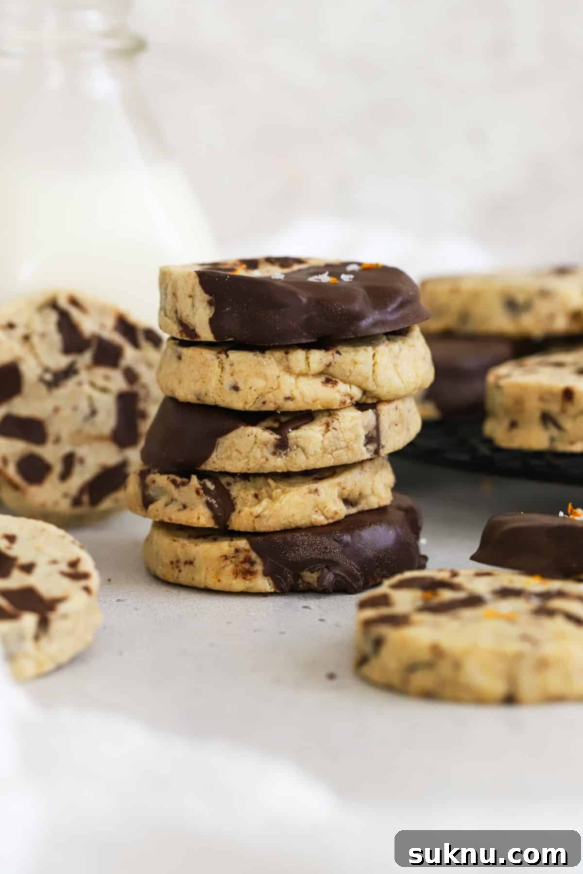 Wholesome Gluten-Free Orange Chocolate Buttery Bites 7 Gluten-Free Orange Chocolate Chunk Shortbread Cookies stacked next to a bottle of milk.