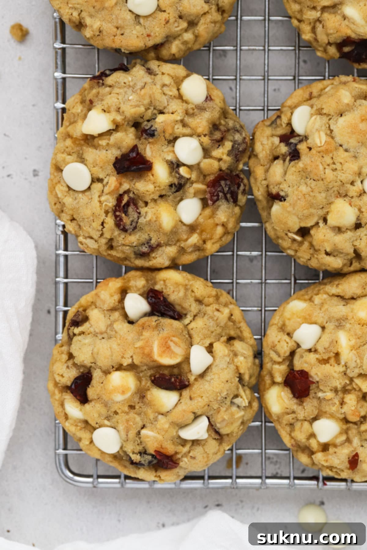 Gluten-free cranberry white chocolate oatmeal cookies cooling on a wire rack, showcasing their chewy texture and festive colors.