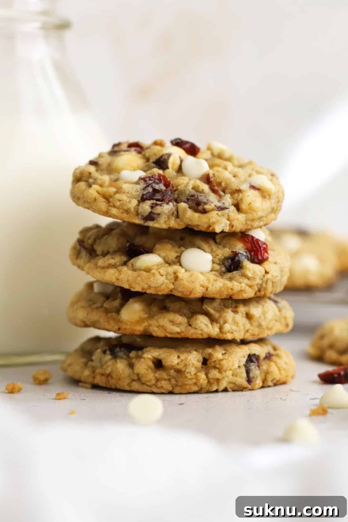 gluten-free cranberry white chocolate oatmeal cookies stacked next to a jar of milk