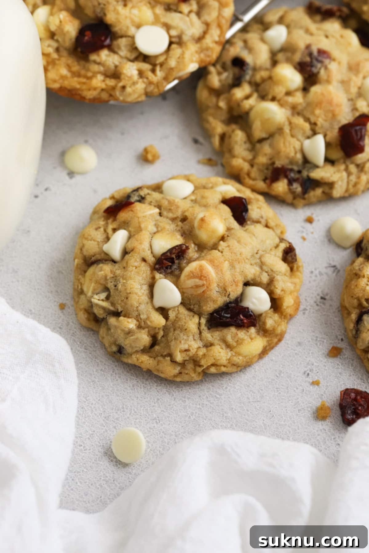 Freshly baked gluten-free cranberry white chocolate chip oatmeal cookies alongside a glass of milk.