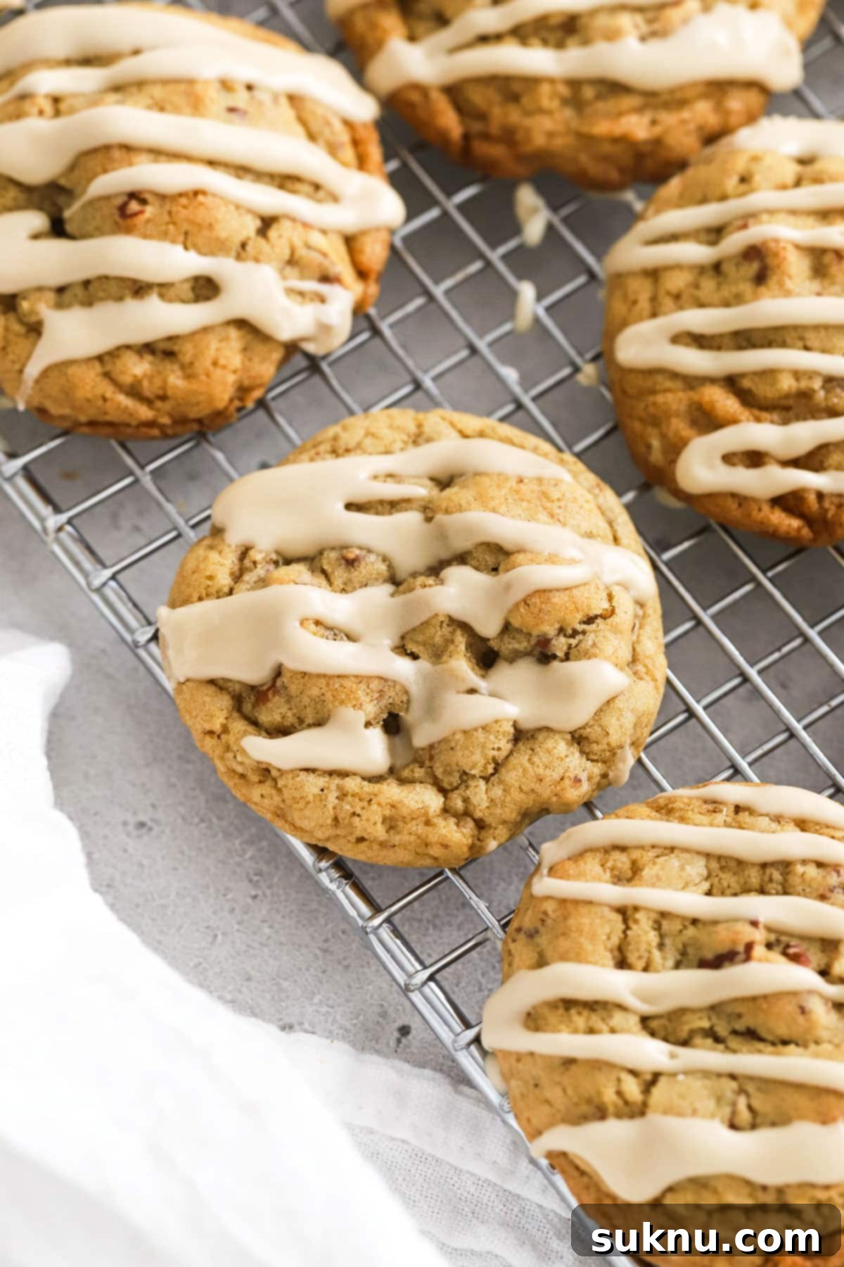 Gluten-free maple pecan cookies with maple glaze cooling on a a wire rack
