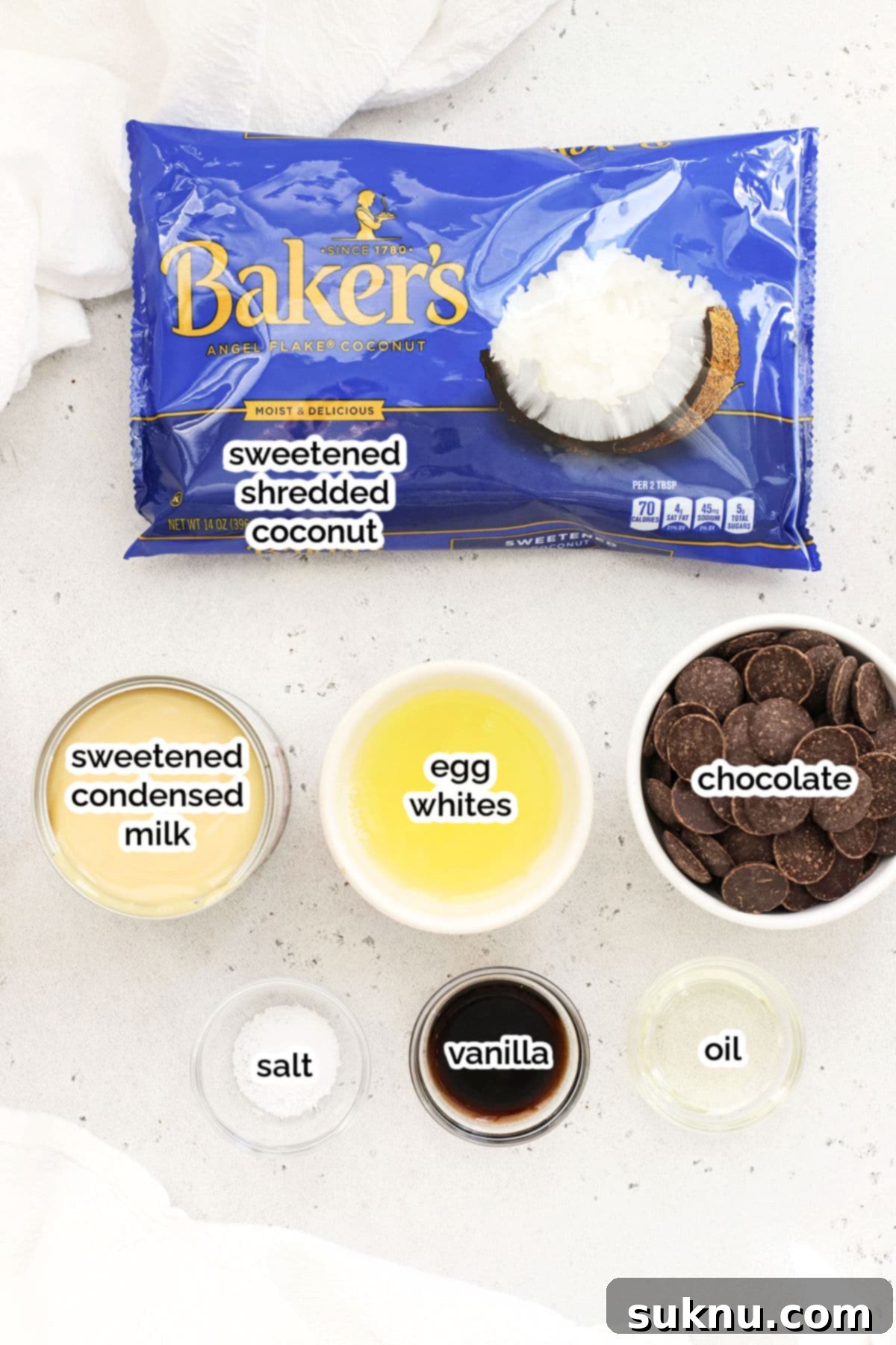 Ingredients for making gluten-free chocolate-dipped coconut macaroons laid out on a surface.
