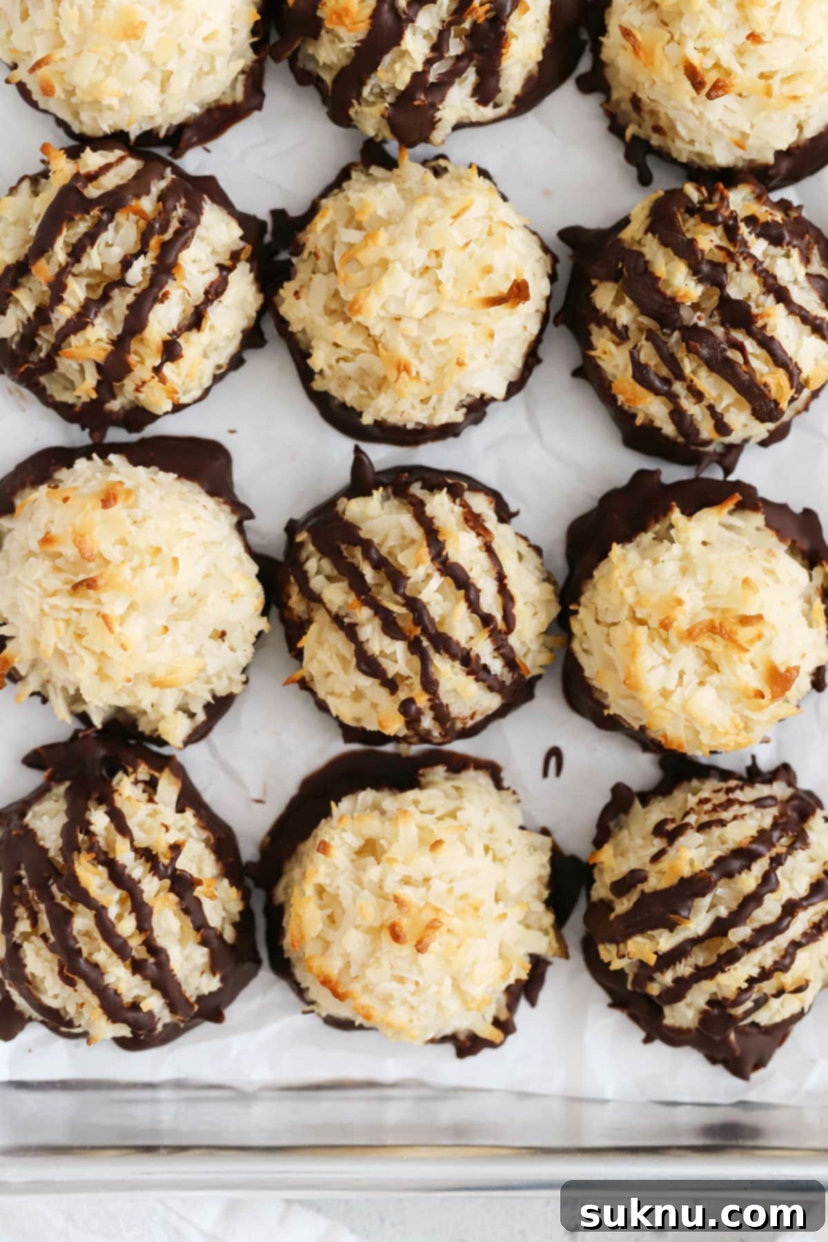 Finished chocolate-dipped coconut macaroons arranged neatly on a baking sheet, ready to be served.