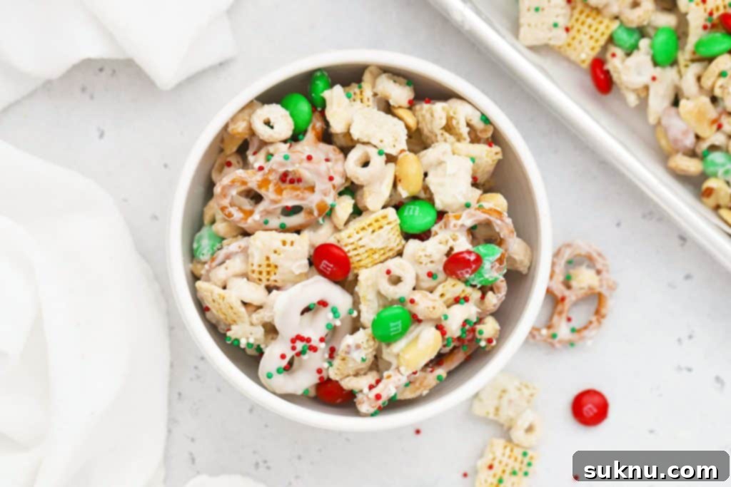 A white bowl of gluten-free christmas chex mix with m&ms and pretzels