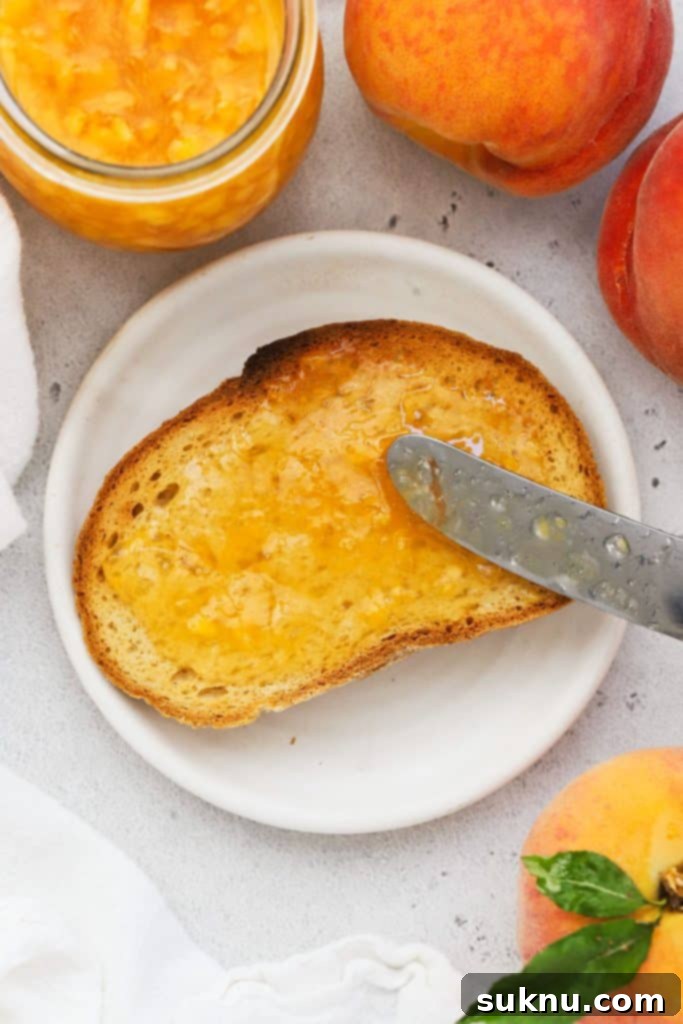 spreading peach freezer jam on a slice of gluten-free toast