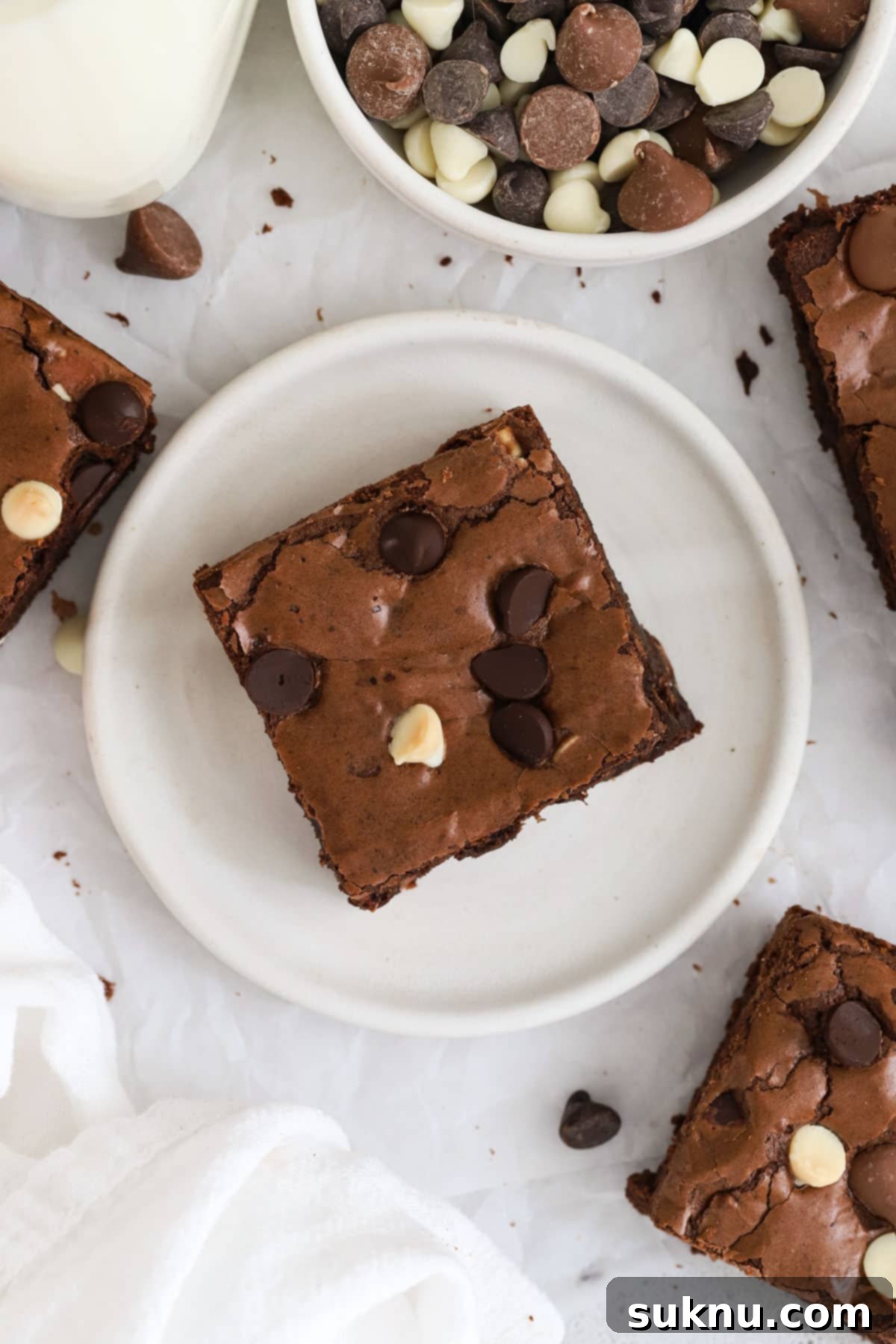 Gluten-free triple chocolate brownies arranged on elegant white dessert plates, showcasing their rich texture and varied chocolate chips.