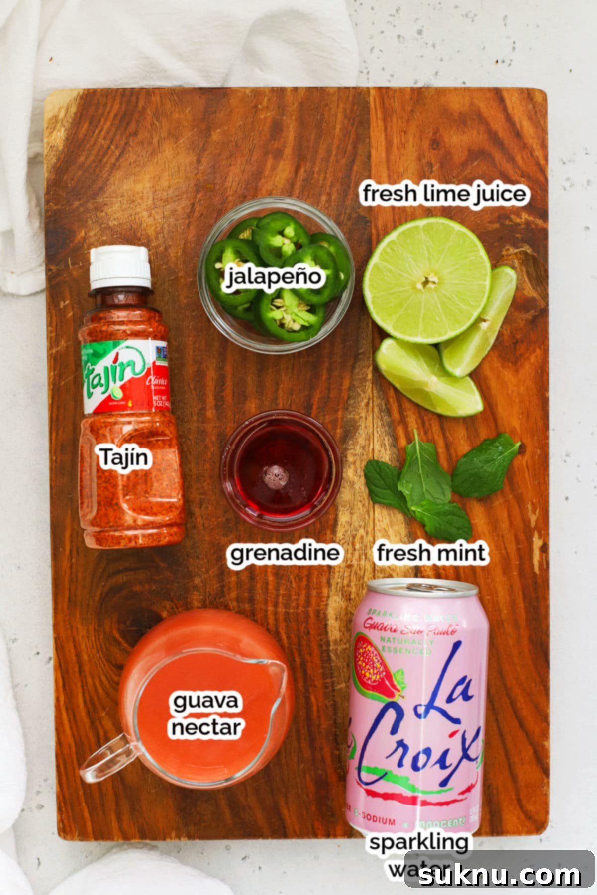 Array of fresh ingredients for a guava mocktail including guava nectar, limes, mint, and jalapeños